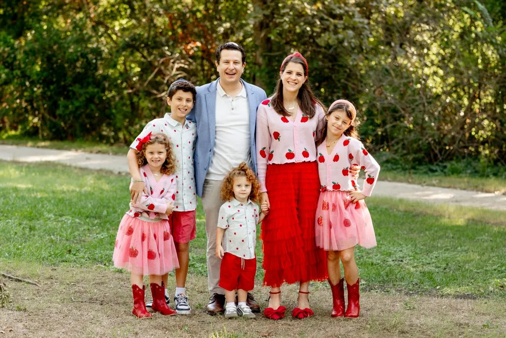 Parents and four children in coordinated pink and red outfits outdoors