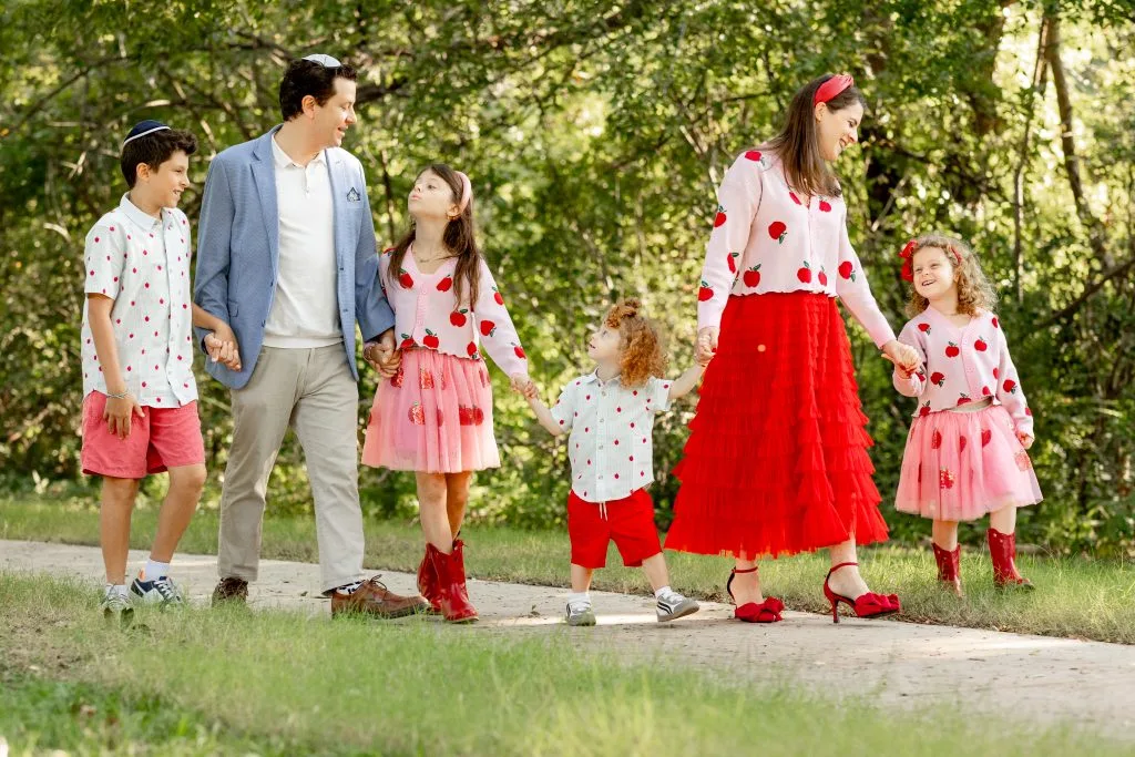 Parents and children holding hands and walking through a green outdoor setting